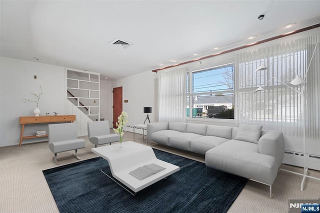 carpeted living area with a baseboard radiator, recessed lighting, and visible vents