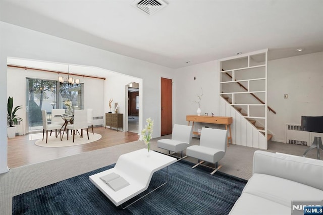 living area with visible vents, radiator, a notable chandelier, and stairway