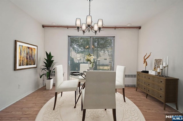 dining room featuring baseboards, radiator, wood finished floors, and a chandelier