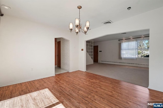 empty room featuring visible vents, a baseboard radiator, wood finished floors, and a chandelier