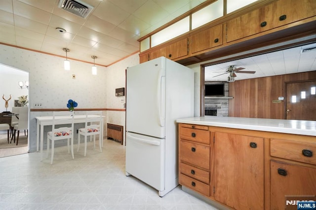 kitchen with visible vents, freestanding refrigerator, wallpapered walls, brown cabinets, and a ceiling fan
