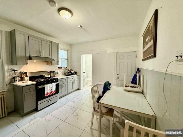 kitchen with gray cabinets, stainless steel range with gas cooktop, marble finish floor, and under cabinet range hood