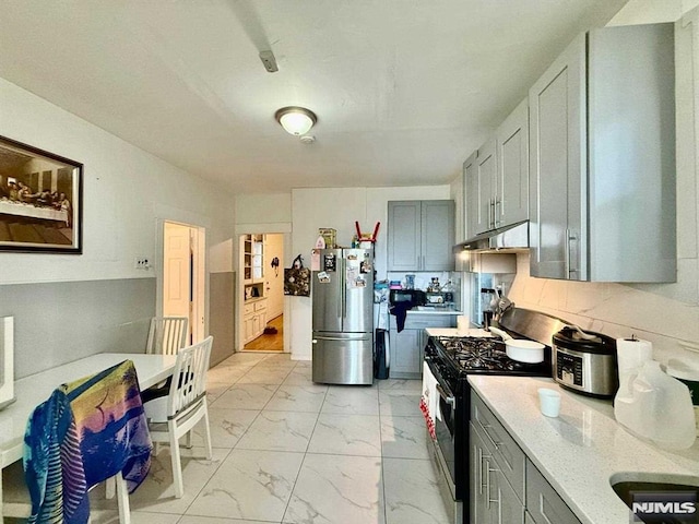 kitchen featuring black range with gas cooktop, freestanding refrigerator, under cabinet range hood, gray cabinets, and marble finish floor