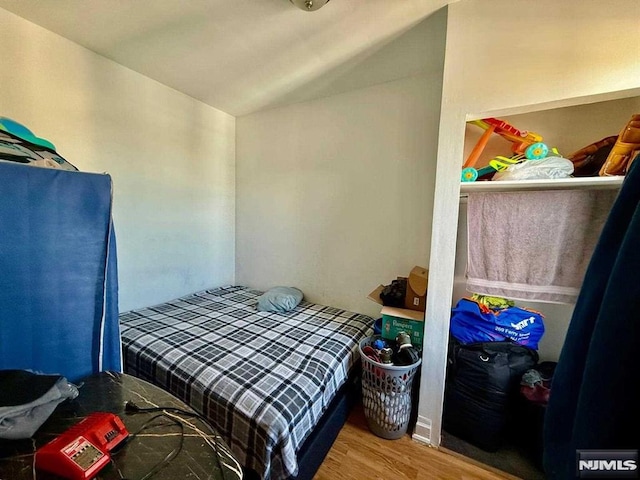 bedroom with wood finished floors and lofted ceiling
