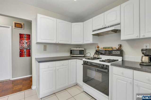 2150 Center Ave Unit 19A, Fort Lee, NJ 07024 - kitchen featuring under cabinet range hood, range with gas stovetop, stainless steel microwave, dark countertops, and white cabinetry