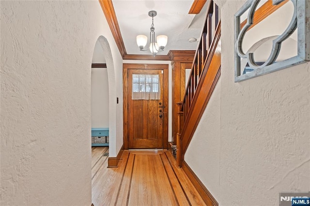 126 Beech St, Nutley, NJ 07110 - doorway to outside featuring a textured wall, arched walkways, a chandelier, crown molding, and light wood-style flooring