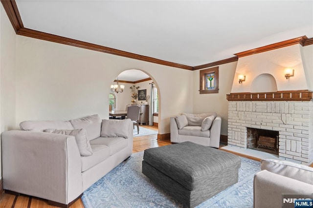 126 Beech St, Nutley, NJ 07110 - living room with arched walkways, ornamental molding, light wood-style floors, a fireplace, and a chandelier