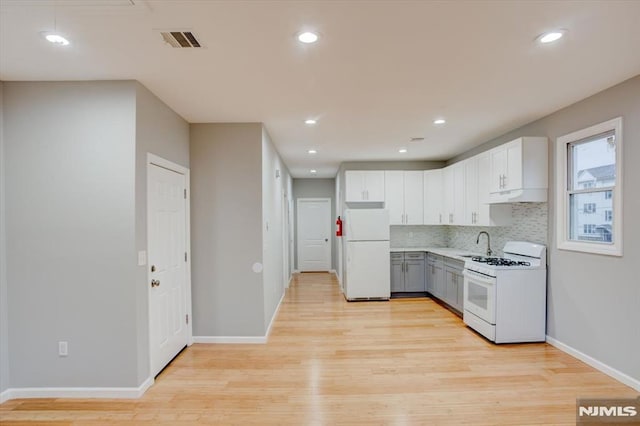 229 21st St, Irvington, NJ 07111 - kitchen with white appliances, visible vents, under cabinet range hood, light wood finished floors, and backsplash