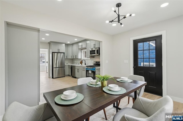 dining area with recessed lighting, baseboards, light wood-style floors, and a notable chandelier