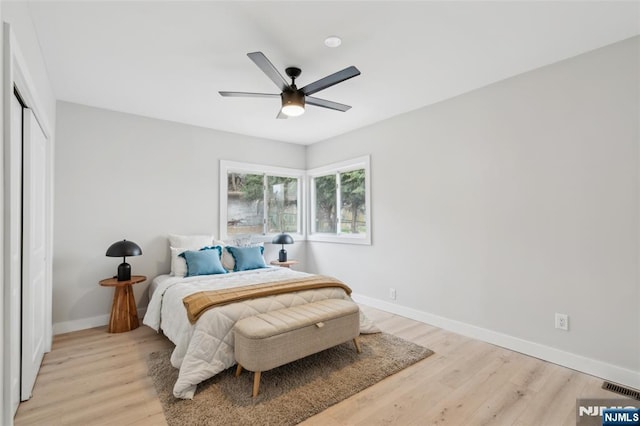 bedroom with a closet, ceiling fan, light wood-style flooring, baseboards, and visible vents