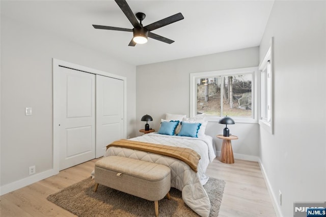 bedroom featuring light wood finished floors, a ceiling fan, baseboards, and a closet