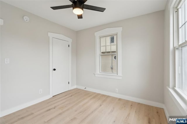 empty room featuring wood finished floors, baseboards, and ceiling fan