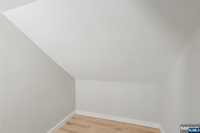 bonus room featuring lofted ceiling, light wood-style flooring, and baseboards