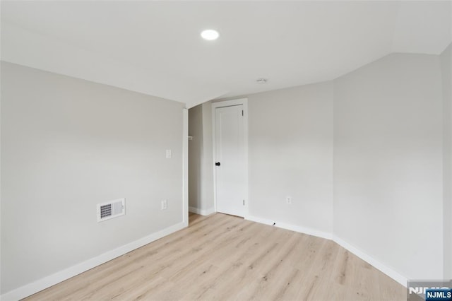 unfurnished room featuring recessed lighting, lofted ceiling, wood finished floors, visible vents, and baseboards