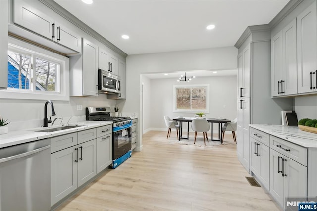 kitchen featuring a wealth of natural light, gray cabinetry, a sink, and appliances with stainless steel finishes