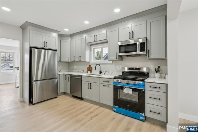 kitchen featuring light countertops, appliances with stainless steel finishes, a sink, and gray cabinetry
