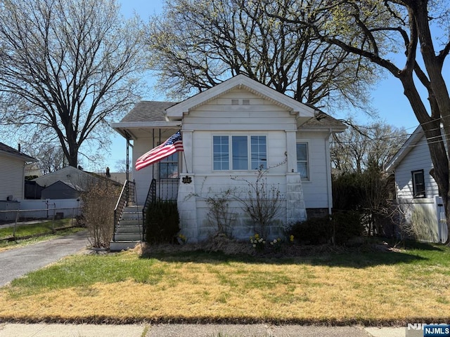 bungalow-style house featuring a front lawn, fence, and aphalt driveway