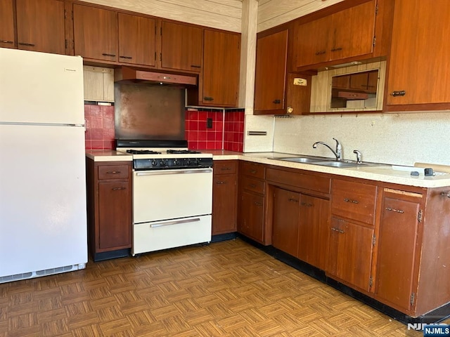 kitchen featuring tasteful backsplash, a sink, white appliances, light countertops, and under cabinet range hood