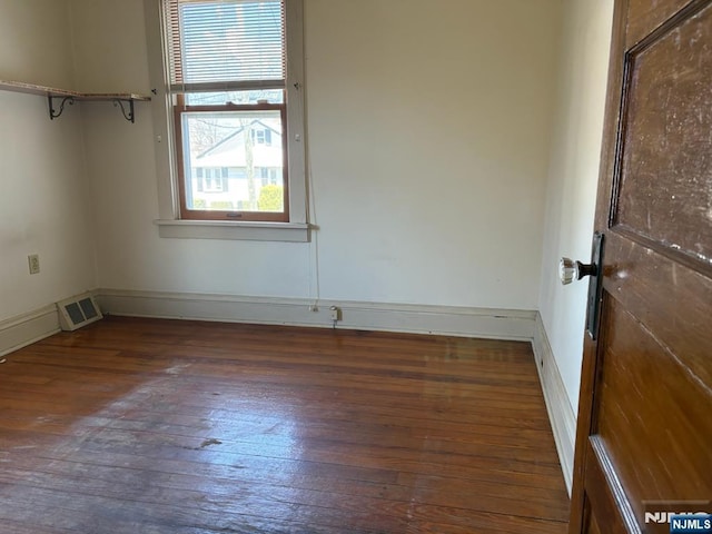 spare room featuring baseboards, visible vents, and wood-type flooring