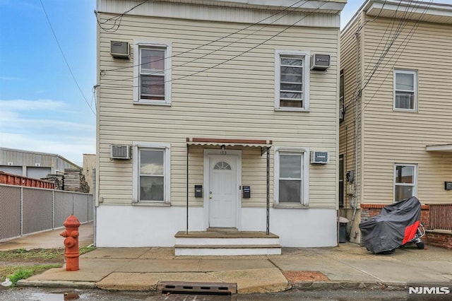 view of front of house with fence and a wall unit AC