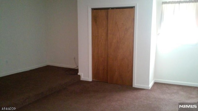 unfurnished bedroom featuring a closet, baseboards, and carpet floors