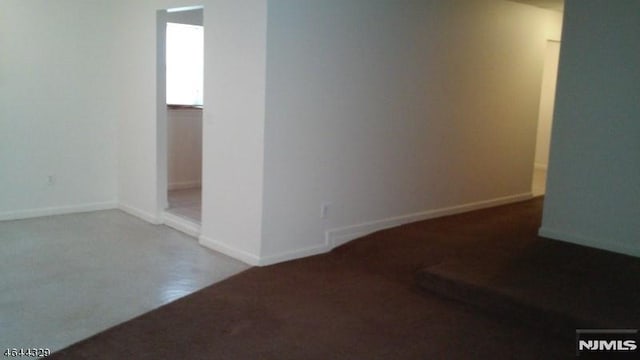 carpeted empty room featuring baseboards