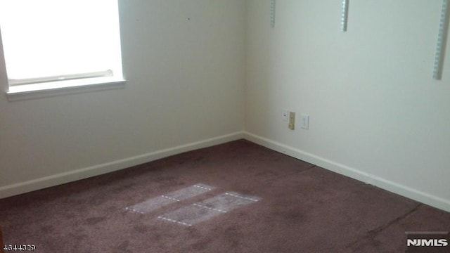 spare room featuring carpet flooring and baseboards