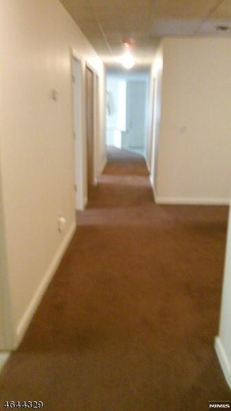 hallway featuring carpet and baseboards
