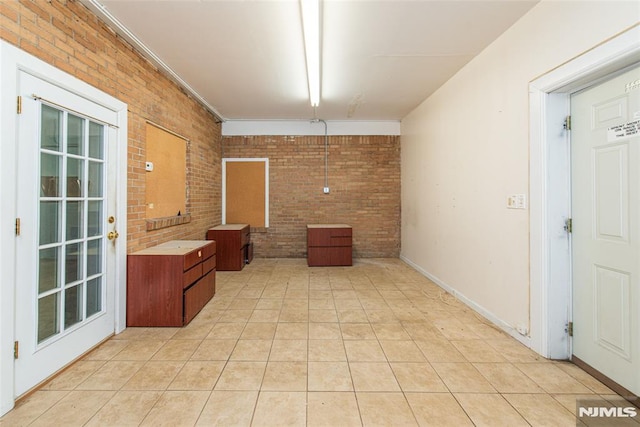 unfurnished dining area featuring light tile patterned flooring and brick wall