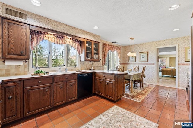 kitchen featuring wallpapered walls, visible vents, a sink, a peninsula, and black dishwasher