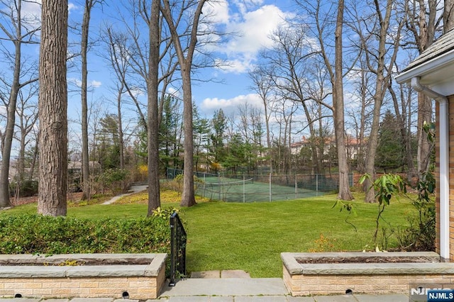 view of yard featuring a tennis court and fence