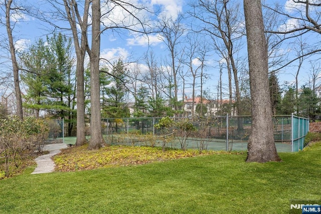 view of yard with fence and a tennis court