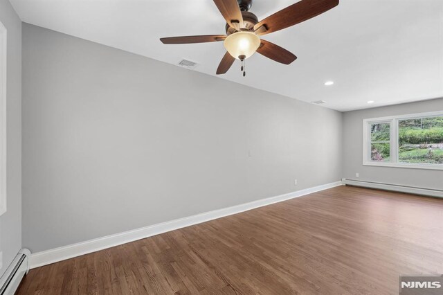 empty room featuring visible vents, wood finished floors, baseboard heating, a baseboard heating unit, and a ceiling fan