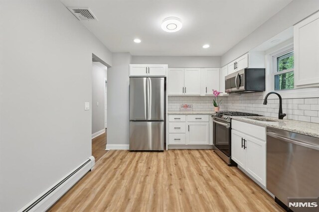 kitchen featuring a sink, visible vents, stainless steel appliances, decorative backsplash, and a baseboard heating unit