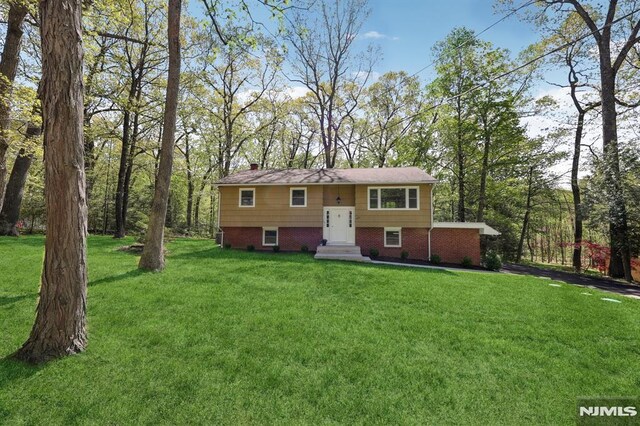 bi-level home with a chimney, brick siding, and a front yard