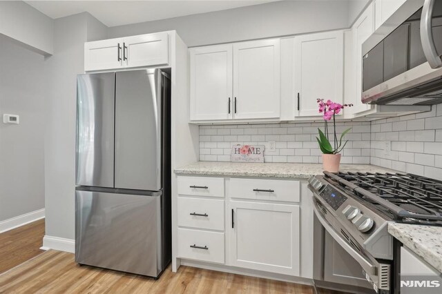kitchen featuring baseboards, white cabinets, stainless steel appliances, and tasteful backsplash