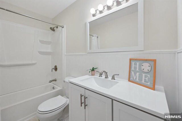 bathroom featuring vanity, wainscoting, shower / bath combination with curtain, and toilet