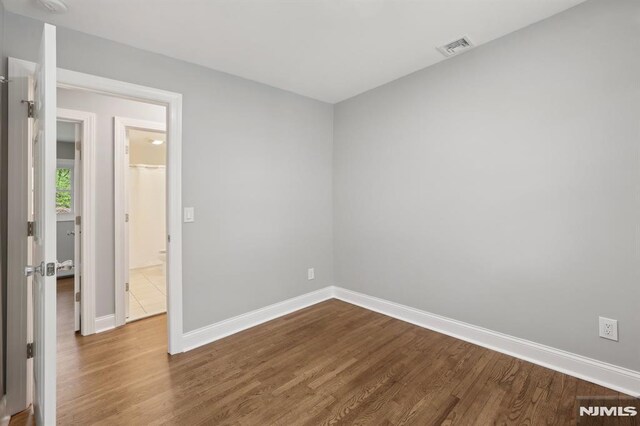 empty room featuring baseboards, visible vents, and dark wood-type flooring