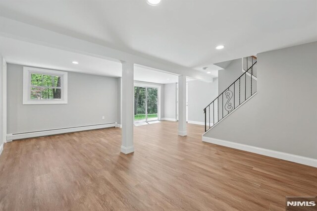 unfurnished living room with baseboards, stairway, recessed lighting, a baseboard radiator, and light wood finished floors