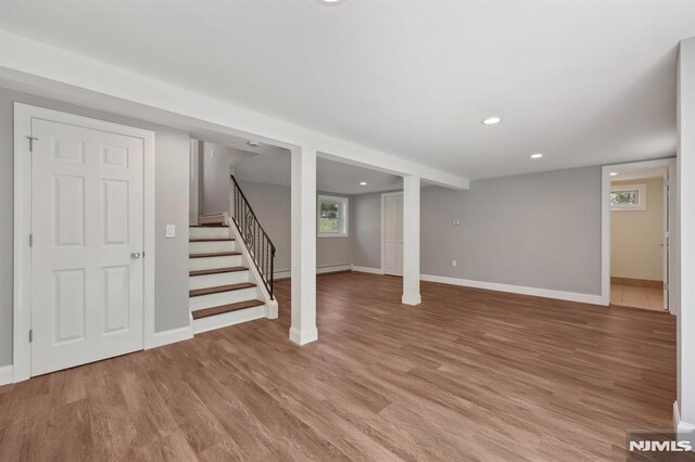 below grade area featuring baseboards, stairway, and light wood-type flooring
