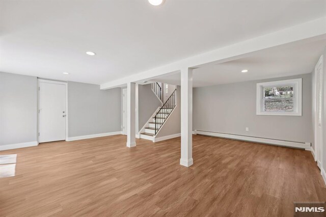 basement with baseboard heating, light wood-type flooring, stairs, baseboards, and recessed lighting