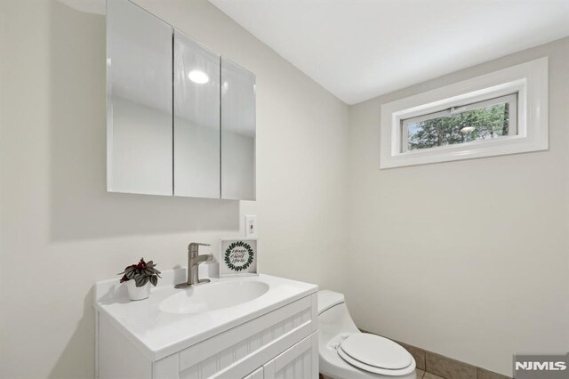 half bathroom featuring vanity, tile patterned floors, and toilet