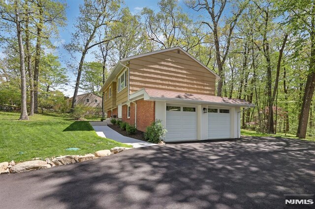 view of side of home featuring a lawn, aphalt driveway, and brick siding