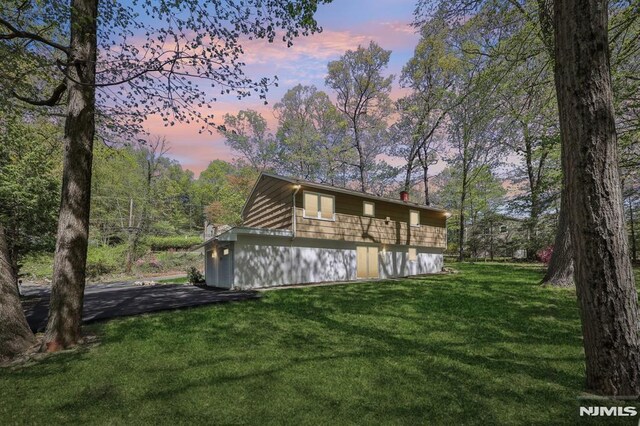 back of house at dusk with a lawn
