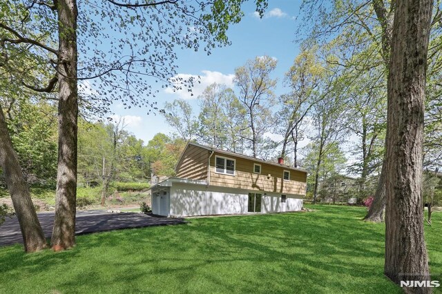 rear view of house featuring a lawn and a chimney