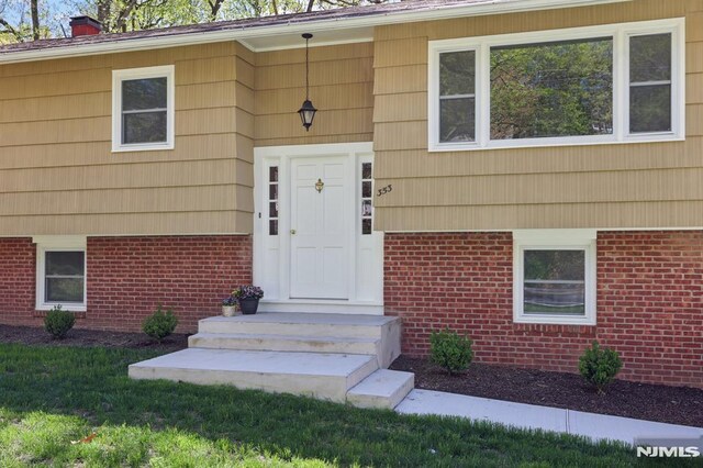 entrance to property with a lawn, a chimney, and brick siding