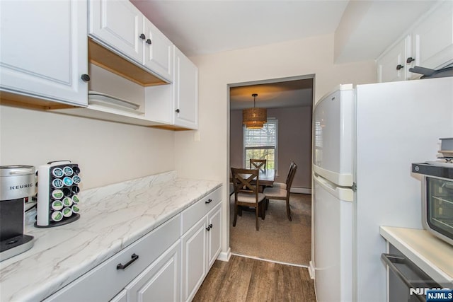 kitchen featuring a baseboard heating unit, freestanding refrigerator, white cabinets, light stone countertops, and dark wood-type flooring