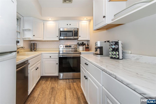 kitchen featuring a sink, tasteful backsplash, appliances with stainless steel finishes, and white cabinetry