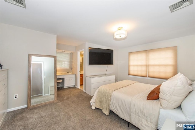 carpeted bedroom with visible vents, baseboards, and ensuite bathroom