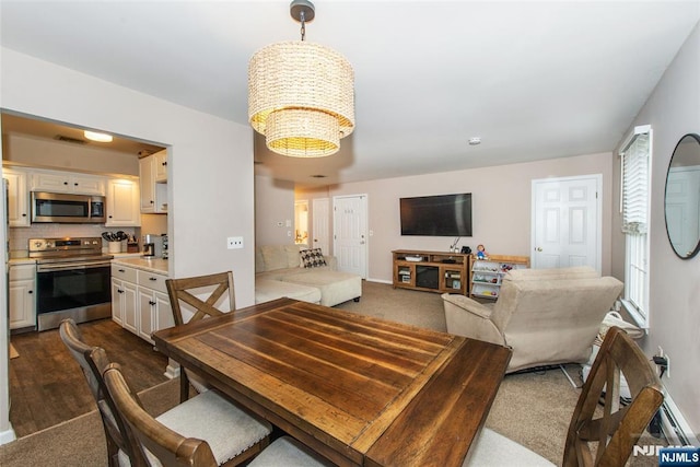 dining room with dark colored carpet, visible vents, and an inviting chandelier
